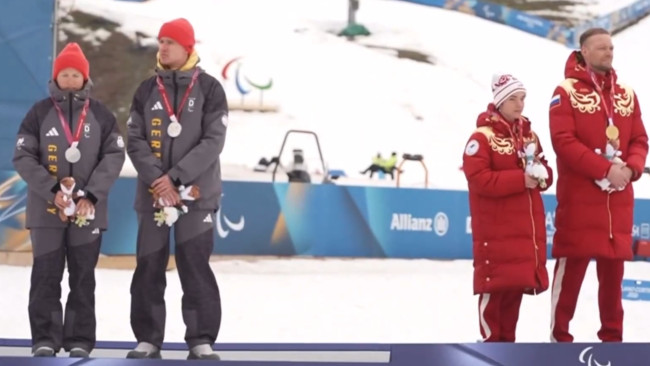 ドイツのスキーヤーたちが冬季パラリンピックの表彰台でロシア人に背を向けている